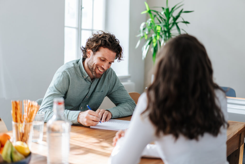 Zwei Personen sitzen beim Schreibtisch und arbeiten